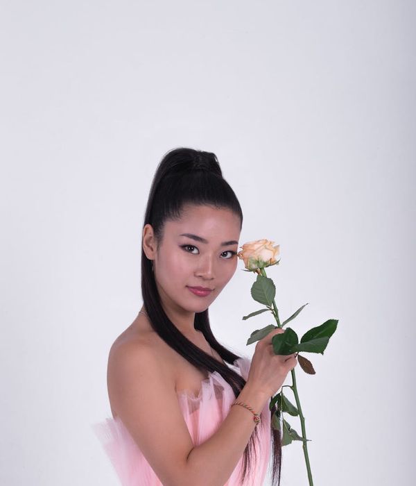 Woman in a graceful yoga pose with soft pink light accents.